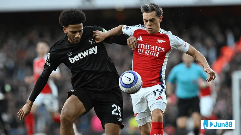 Cầu thủ Arsenal với chiếc áo đỏ và cầu thủ West Ham trong áo màu xanh đang tranh chấp bóng…